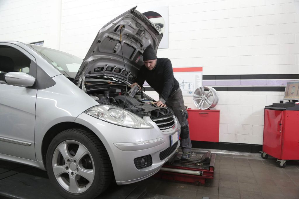 mechanic repairing silver hatchback car